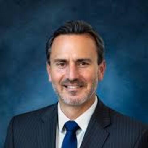 Ray Mueller smiling in a professional headshot, wearing a dark suit