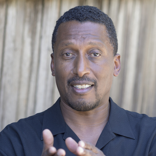 RJ Jennings smiling and speaking with his hands mid-gesture, wearing a dark shirt