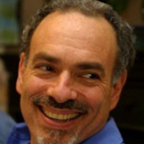Robert Brownstone smiling broadly outdoors, wearing a blue button-down shirt
