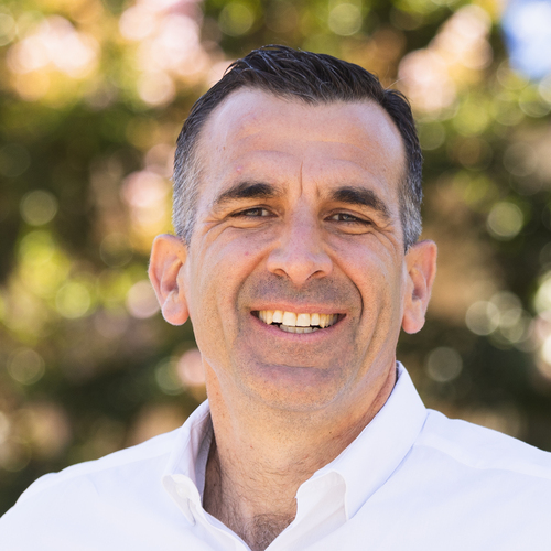 Sam Liccardo smiling outdoors, wearing a white button-down shirt
