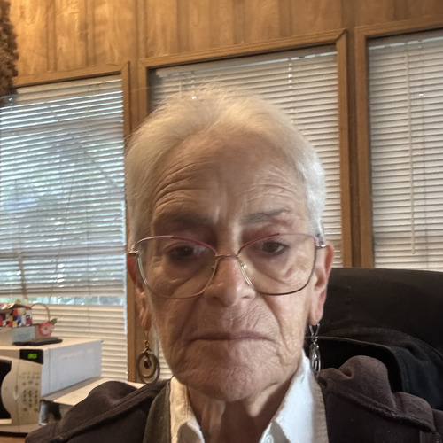 Willa J Chapman in a close-up portrait, wearing glasses and a dark jacket